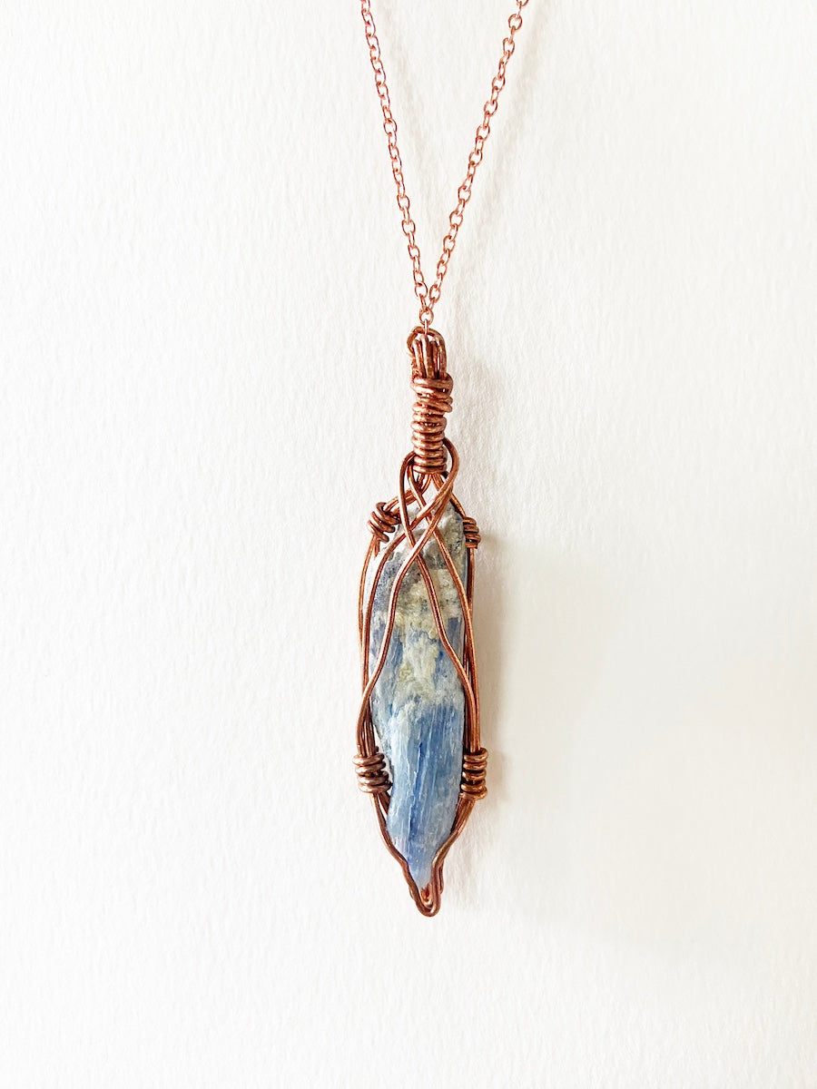 Blue Kyanite Wire-Wrapped Copper Pendant Necklace. Genuine Real Raw Crystal Gemstone Sourced in Asheville, North Carolina. Minimalist Modern Bohemian Style with Criss-Cross Design. Authentic One-of-a-Kind Handmade Jewelry.